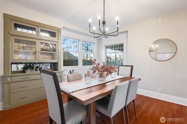 dining space featuring baseboards, an inviting chandelier, and wood finished floors