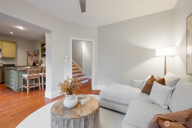 living area featuring light wood finished floors, recessed lighting, a ceiling fan, baseboards, and stairs