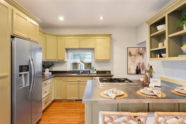 kitchen with stainless steel appliances, cream cabinets, light wood-type flooring, and a sink