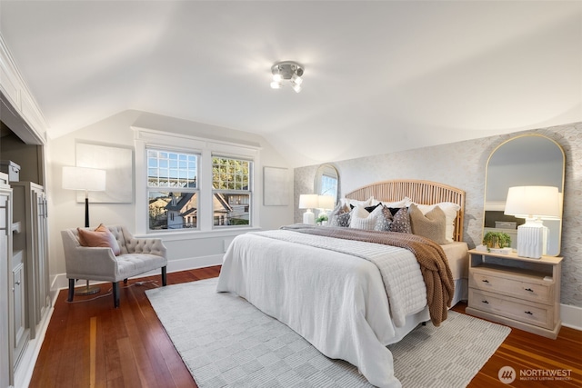 bedroom featuring lofted ceiling, wallpapered walls, and dark wood-type flooring