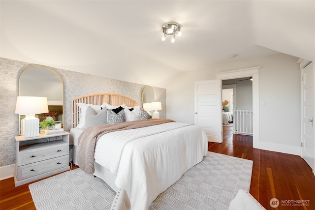 bedroom with baseboards, vaulted ceiling, wood finished floors, and wallpapered walls