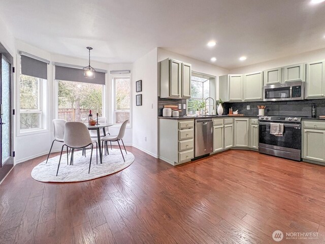 kitchen featuring tasteful backsplash, appliances with stainless steel finishes, dark wood-type flooring, and a sink