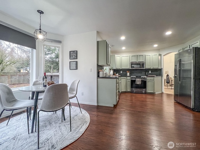 dining area featuring baseboards, arched walkways, dark wood-type flooring, and recessed lighting