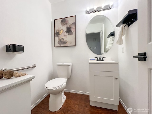 half bathroom featuring baseboards, vanity, toilet, and wood finished floors