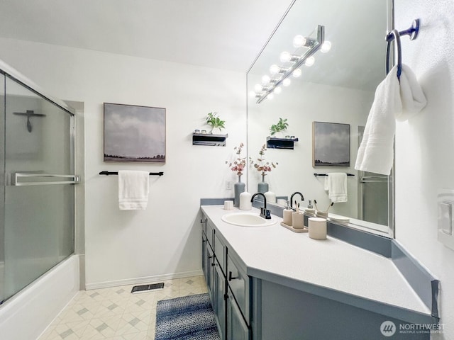 bathroom with combined bath / shower with glass door, vanity, and baseboards