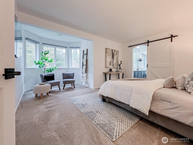 carpeted bedroom featuring a barn door, ensuite bath, and baseboards