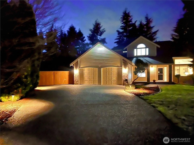 view of front of home with an outbuilding, an attached garage, fence, stone siding, and driveway