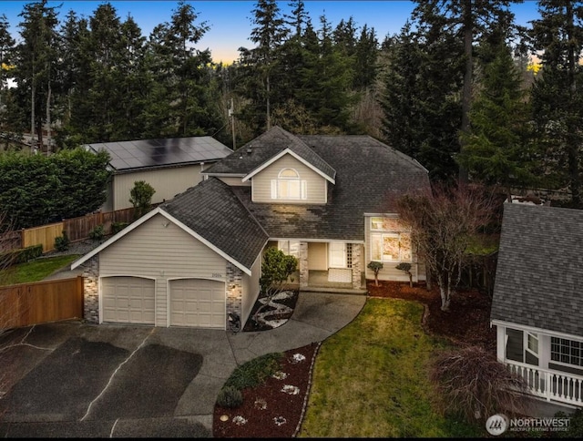 view of front of house featuring roof with shingles, concrete driveway, an attached garage, and fence