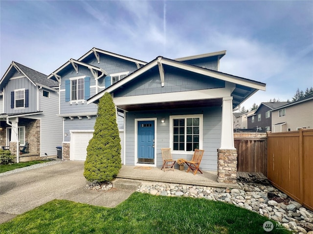 craftsman-style home with a garage, a porch, driveway, and fence