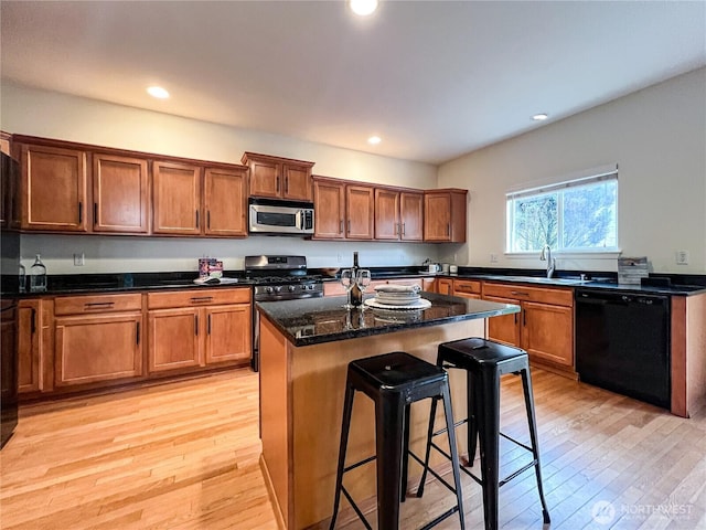 kitchen featuring a kitchen breakfast bar, light wood-style floors, appliances with stainless steel finishes, and a sink