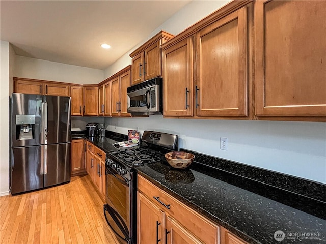 kitchen with black gas range oven, stainless steel microwave, light wood-type flooring, fridge with ice dispenser, and brown cabinetry