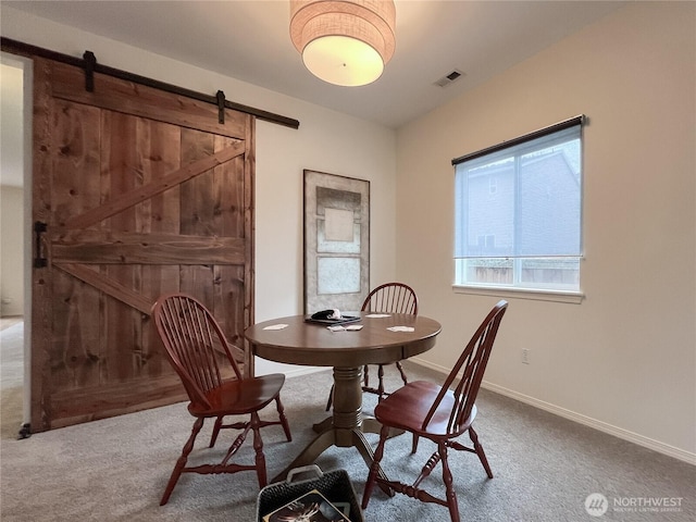 carpeted dining room with visible vents, baseboards, and a barn door