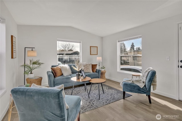 living area with baseboards, vaulted ceiling, and wood finished floors