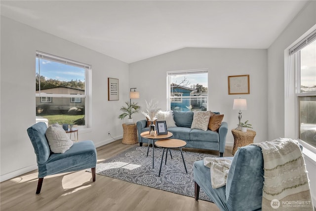 living area with vaulted ceiling, baseboards, and wood finished floors