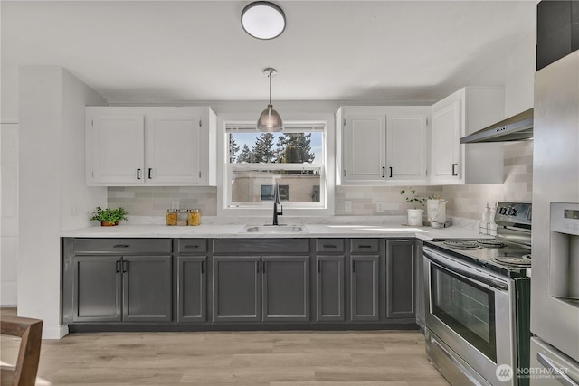 kitchen with light countertops, backsplash, appliances with stainless steel finishes, white cabinetry, and a sink