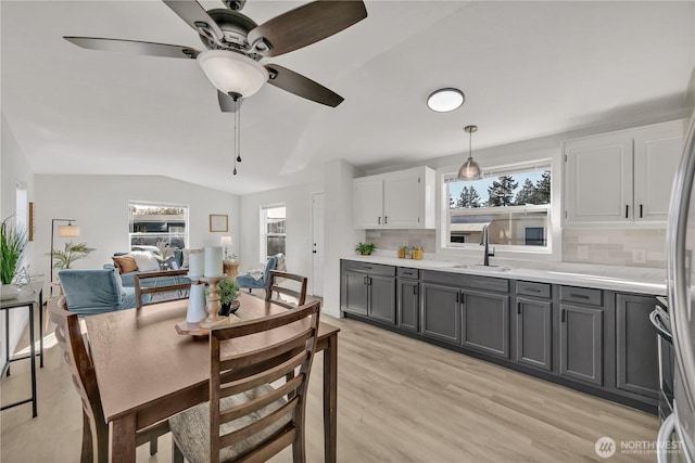 dining space with vaulted ceiling, light wood-type flooring, and a healthy amount of sunlight