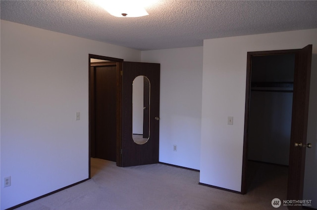 unfurnished bedroom featuring a textured ceiling, carpet floors, a closet, and baseboards