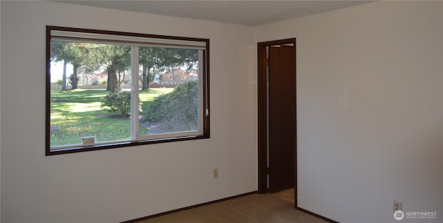 carpeted spare room featuring baseboards and a textured ceiling