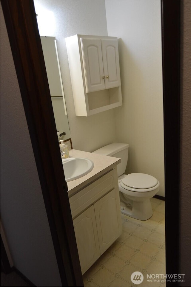 half bath with vanity, toilet, and tile patterned floors