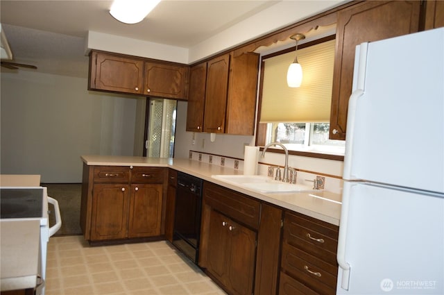 kitchen with dishwasher, stove, freestanding refrigerator, light countertops, and a sink