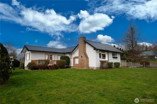 view of property exterior featuring metal roof, a yard, a chimney, and a wooden deck