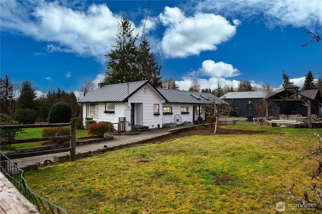 ranch-style home with metal roof, a standing seam roof, a front yard, and fence