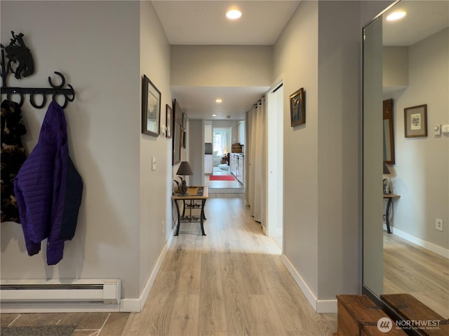 hallway with baseboard heating, light wood-type flooring, and baseboards