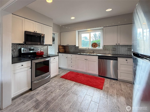 kitchen with appliances with stainless steel finishes, dark countertops, a sink, and tasteful backsplash