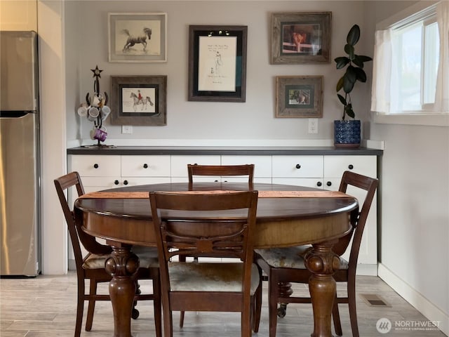 dining area featuring light wood-type flooring, visible vents, and baseboards