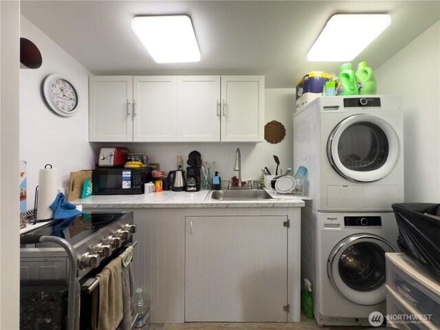 clothes washing area featuring a sink, laundry area, and stacked washer / dryer