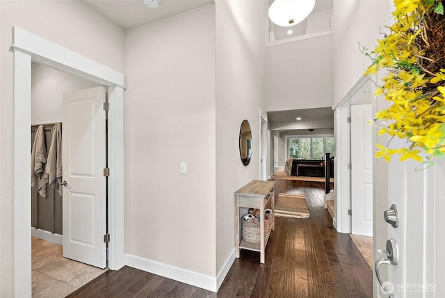 entrance foyer featuring a towering ceiling, baseboards, and wood finished floors