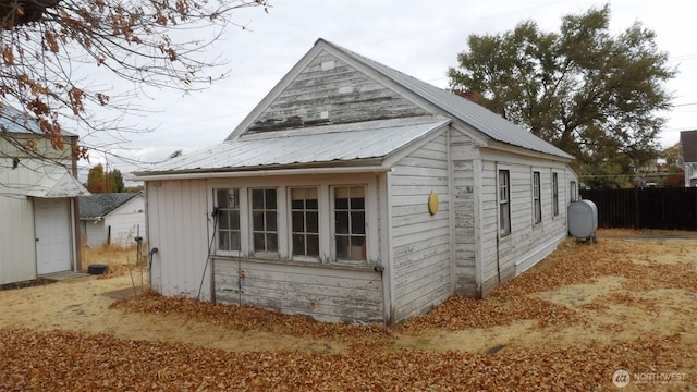 view of side of property featuring metal roof, heating fuel, and fence