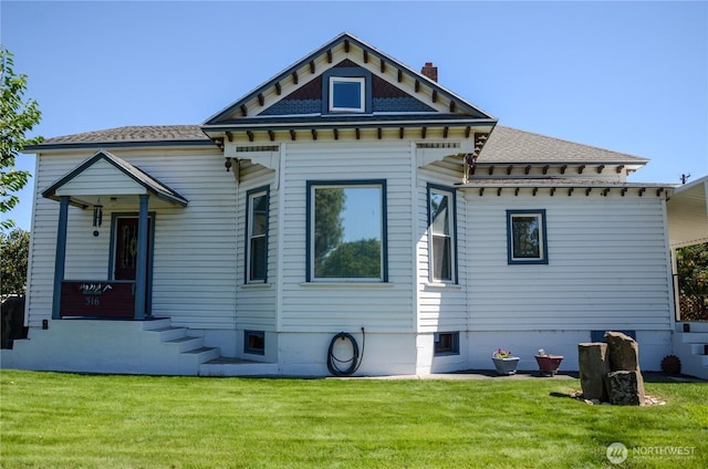 rear view of property featuring a lawn and a chimney