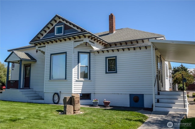 back of house with a shingled roof, a chimney, and a yard