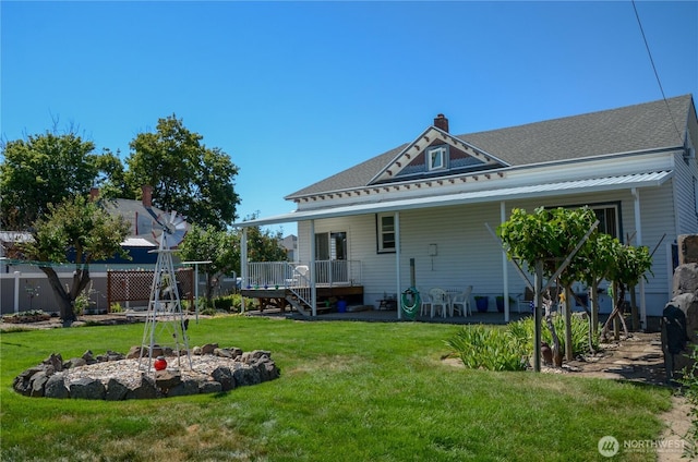 back of house with a shingled roof, a lawn, a chimney, and fence