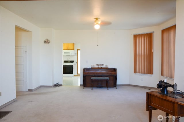 interior space with light colored carpet, ceiling fan, and baseboards