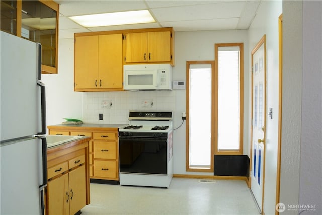 kitchen with white appliances, visible vents, light countertops, a paneled ceiling, and backsplash