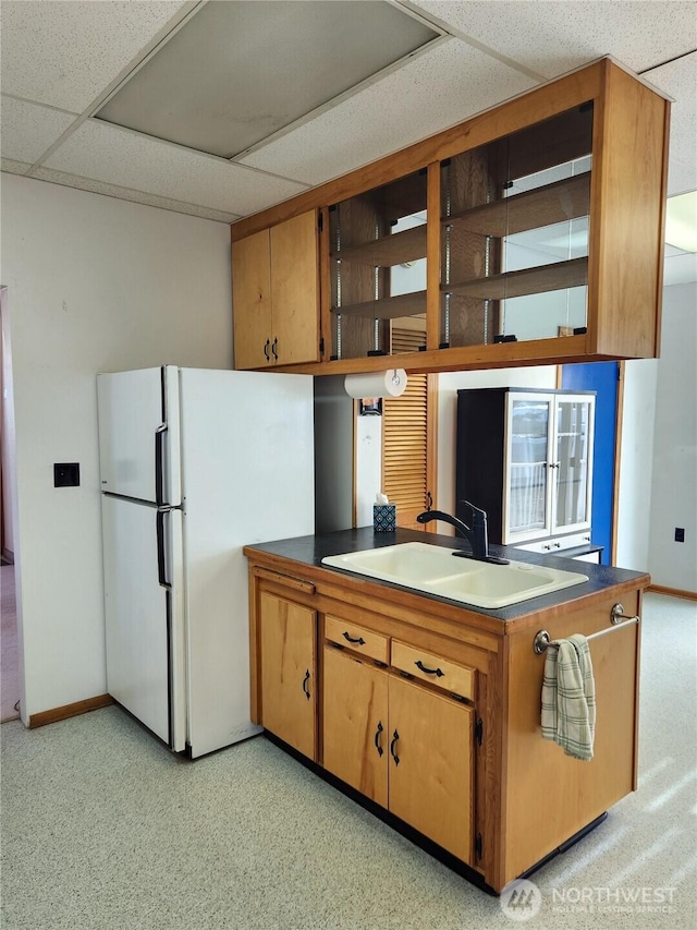 kitchen featuring a paneled ceiling, a peninsula, a sink, freestanding refrigerator, and open shelves