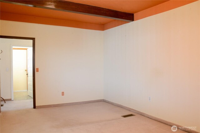 spare room featuring visible vents, light colored carpet, beam ceiling, and baseboards