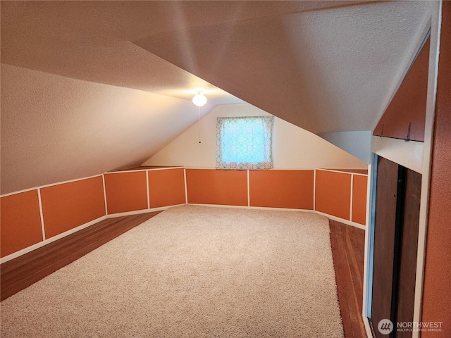 bonus room featuring vaulted ceiling, a textured ceiling, and wood finished floors