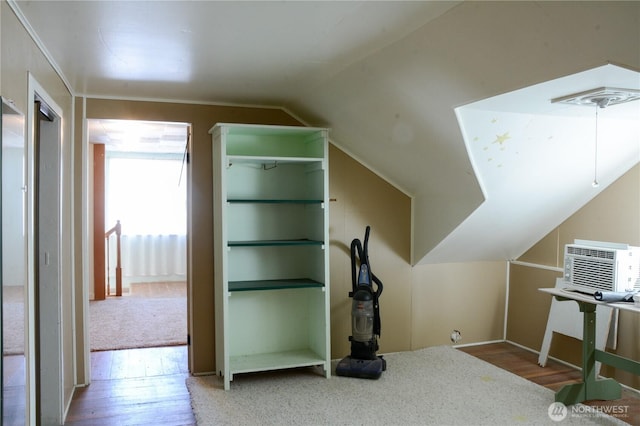 additional living space featuring vaulted ceiling, an AC wall unit, and wood finished floors