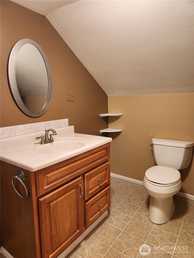 half bathroom featuring baseboards, toilet, vaulted ceiling, a textured ceiling, and vanity