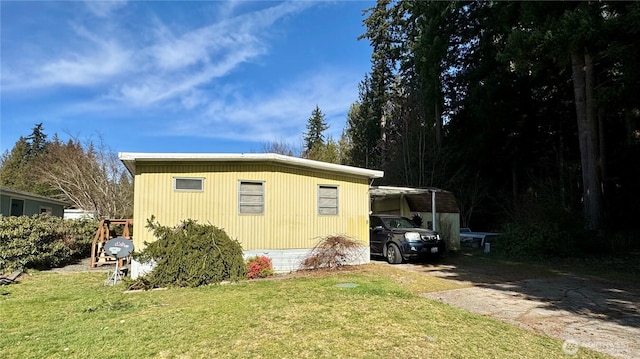 view of property exterior featuring driveway, a lawn, and a detached carport