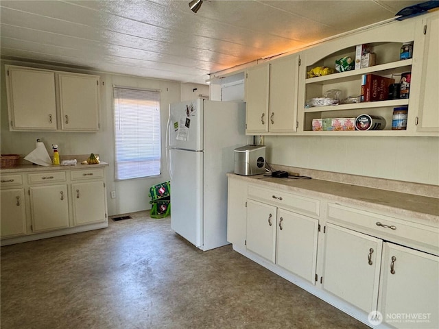 kitchen with freestanding refrigerator, light countertops, concrete floors, and visible vents