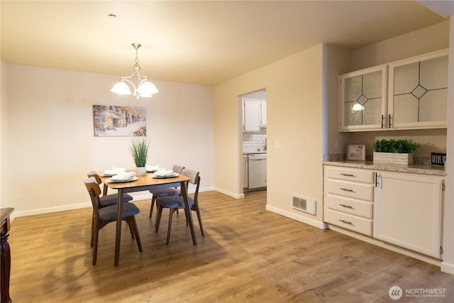 dining space with baseboards, light wood-type flooring, visible vents, and an inviting chandelier