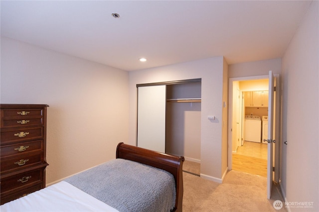 bedroom featuring washing machine and dryer, recessed lighting, light carpet, baseboards, and a closet