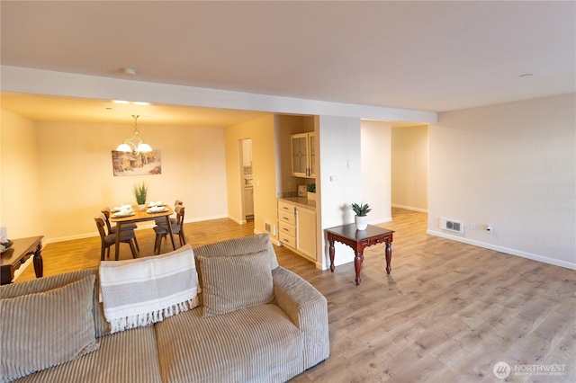 living area featuring light wood-type flooring, visible vents, and baseboards