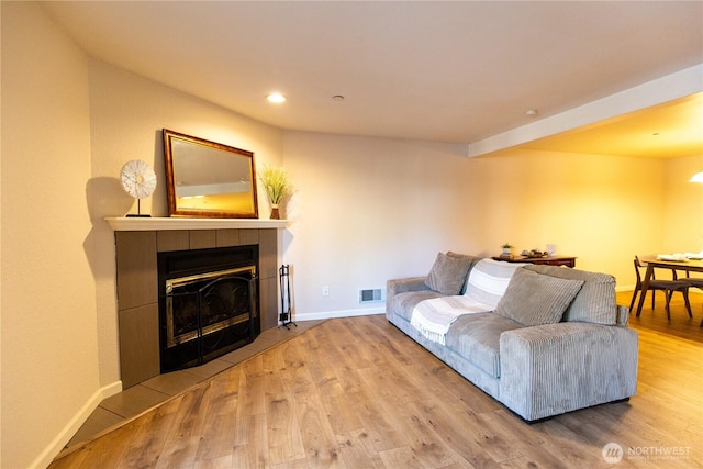 living room featuring visible vents, a fireplace, baseboards, and wood finished floors