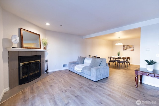 living area featuring baseboards, visible vents, a tile fireplace, wood finished floors, and recessed lighting