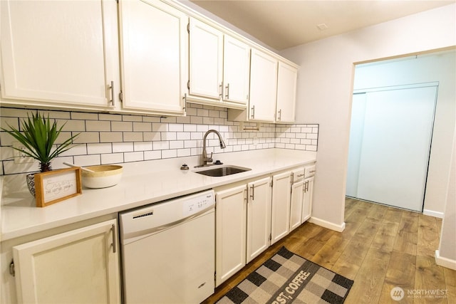 kitchen with light wood-style flooring, white dishwasher, light countertops, and a sink